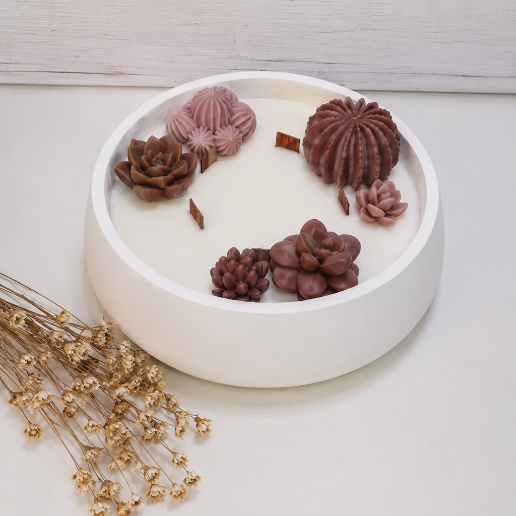 Vela aromática artesanal grande en recipiente blanco decorado con cactus y suculentas