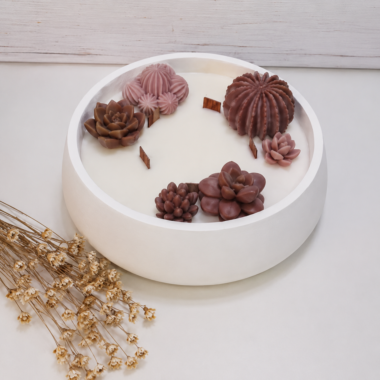 Vela aromática artesanal grande en recipiente blanco decorado con cactus y suculentas